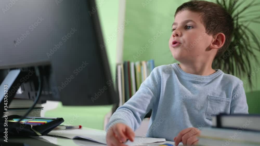 remote training, a little smart boy learns lessons at home sitting at a computer and watches a video lesson with his teacher on a monitor screen while sitting at a desk remote training, a little smart boy learns lessons at home sitting at a computer and watches a video lesson with his teacher on a monitor screen while sitting at a desk