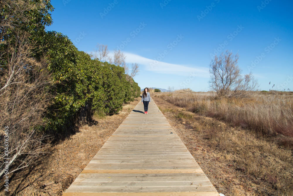 Woman walking on long wooden boardwalk trail