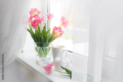 postcard good morning. Still life   a Cup of tea  a bouquet of pink tulips  marshmallows on a light background near the window.