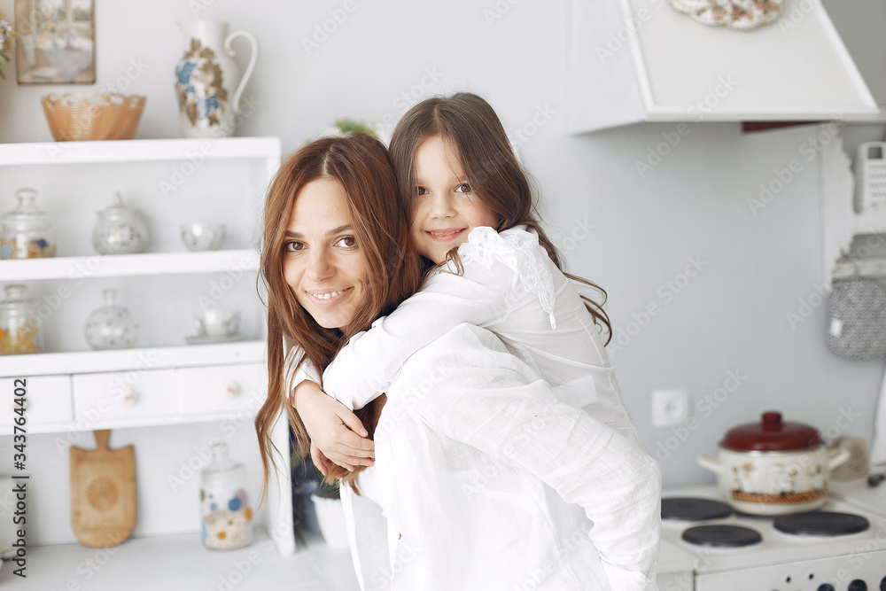 Cute little daughter with mother. Family at home in a kitchen. Woman in a white blouse. Cute little daughter with mother. Family at home in a kitchen. Woman in a white blouse.