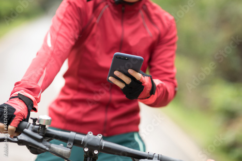 Cyclist use smartphone for navigation when riding mountain bike on forest trail