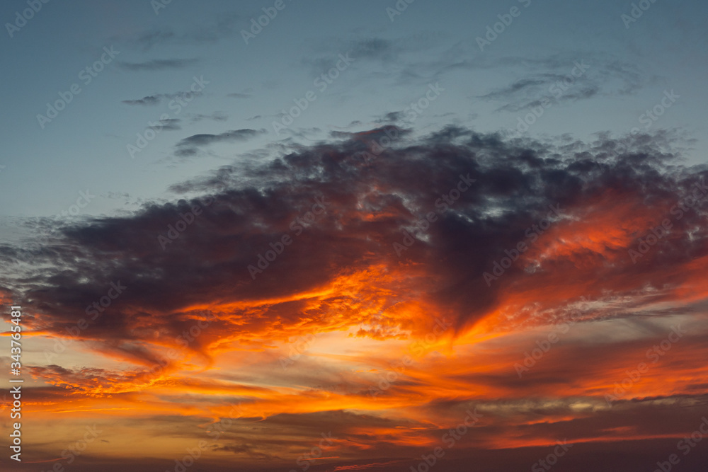 Dramatic sky with clouds and orange sunset at nightfall time