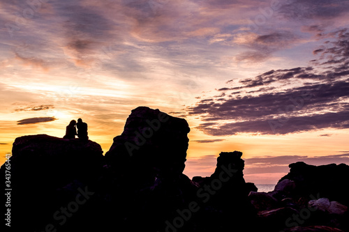 Silhouettes of couple on a rock in sunset. Beautiful romantic view