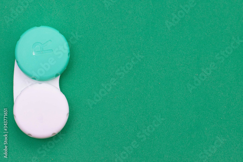 Contact lens container on a green background. Storage o cleaning contact lenses for vision correction, place for text, copy space, the photo