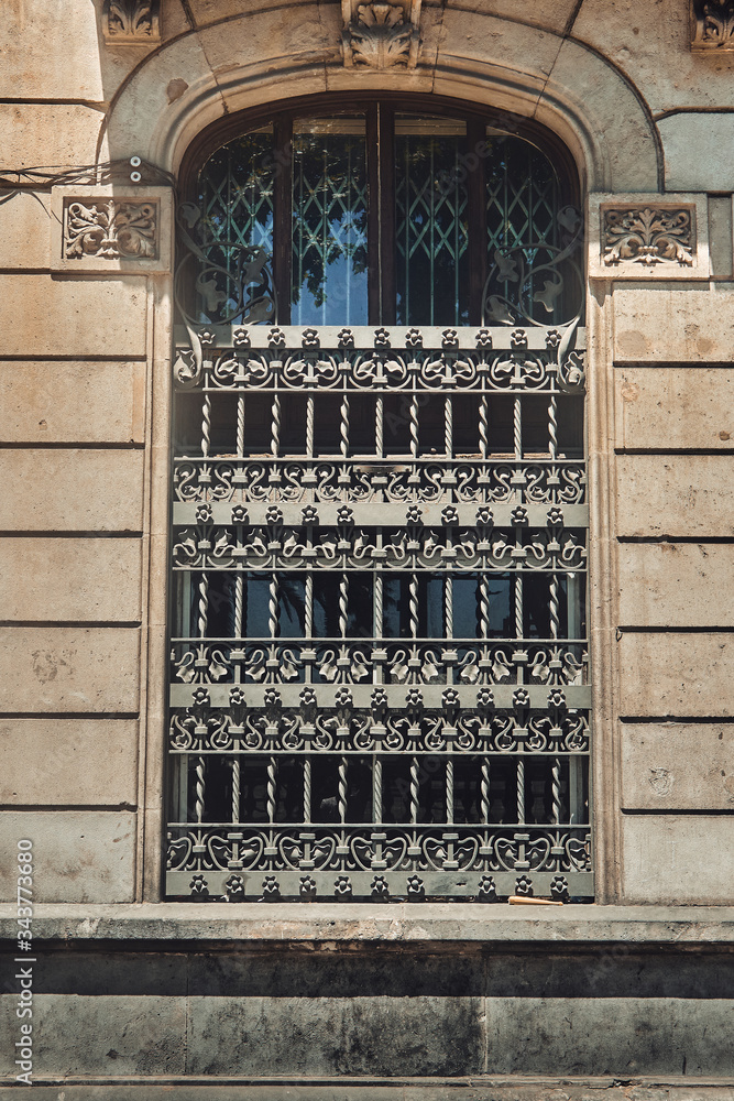 Old window with a beautiful iron bars on a house in a small European city