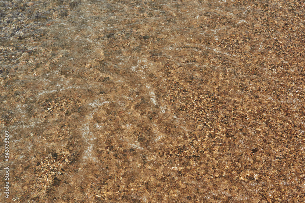 Water near the shore sand texture with small pebbles. Sunny summer day Water near the shore sand texture with small pebbles. Sunny summer day