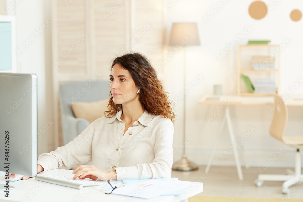 Horizontal medium shot of serious young adult businesswoman working on computer at home Horizontal medium shot of serious young adult businesswoman working on computer at home