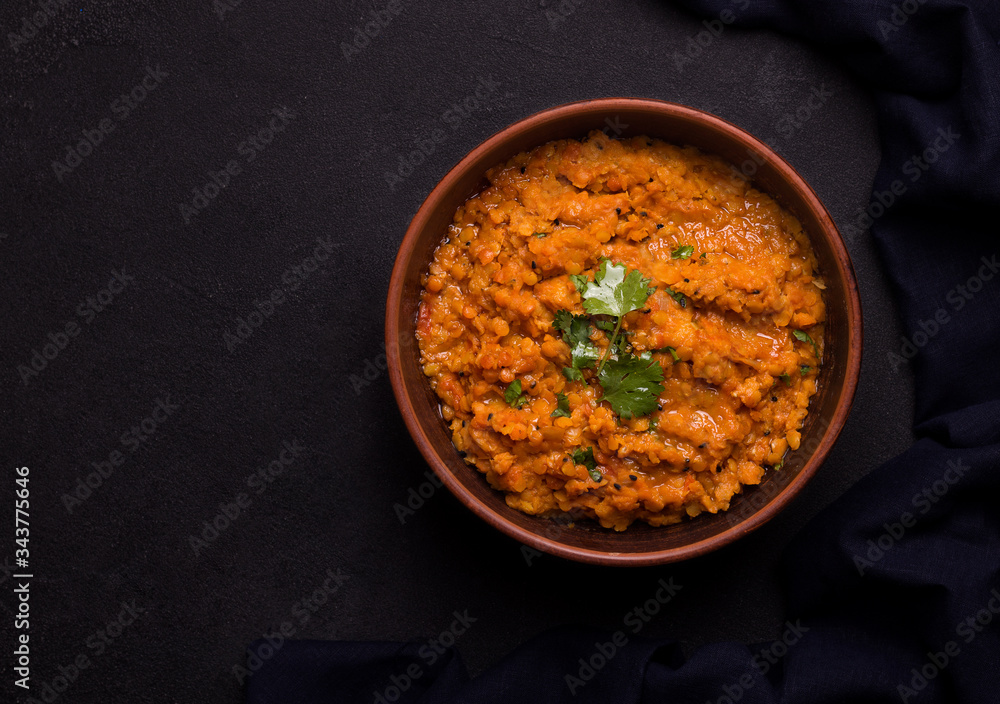 Dhal Indian traditional lentil soup in a clay bowl on a black background copy space. Rustic