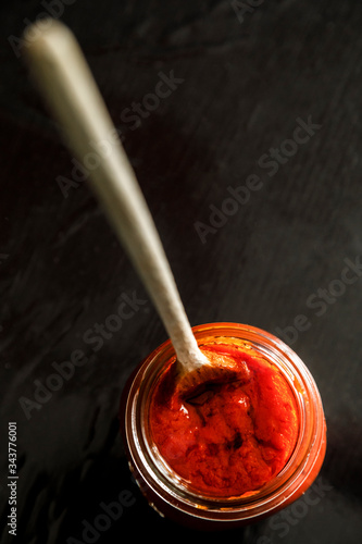 barattolo aperto di passata di pomodoro in fila con dentro un mestolo 