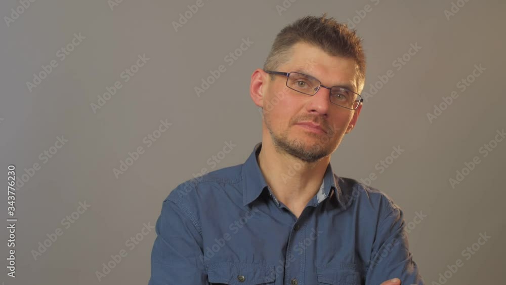 confused guy in blue shirt and glasses looks straight with interest standing against white background close view confused guy in blue shirt and glasses looks straight with interest standing against white background close view