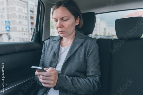Businesswoman text messaging on mobile phone in car © Bits and Splits