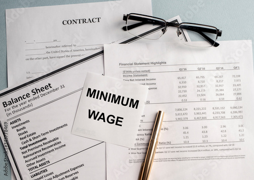 Принти на полотні a paper with MINIMUM WAGE text on backgrounwith documents and glasses