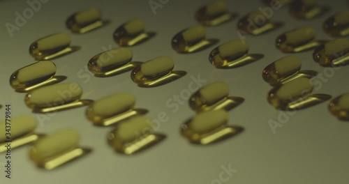 Vitamin supplement cod liver oil capsules in a line reflect liquid inside as light moves across. photo