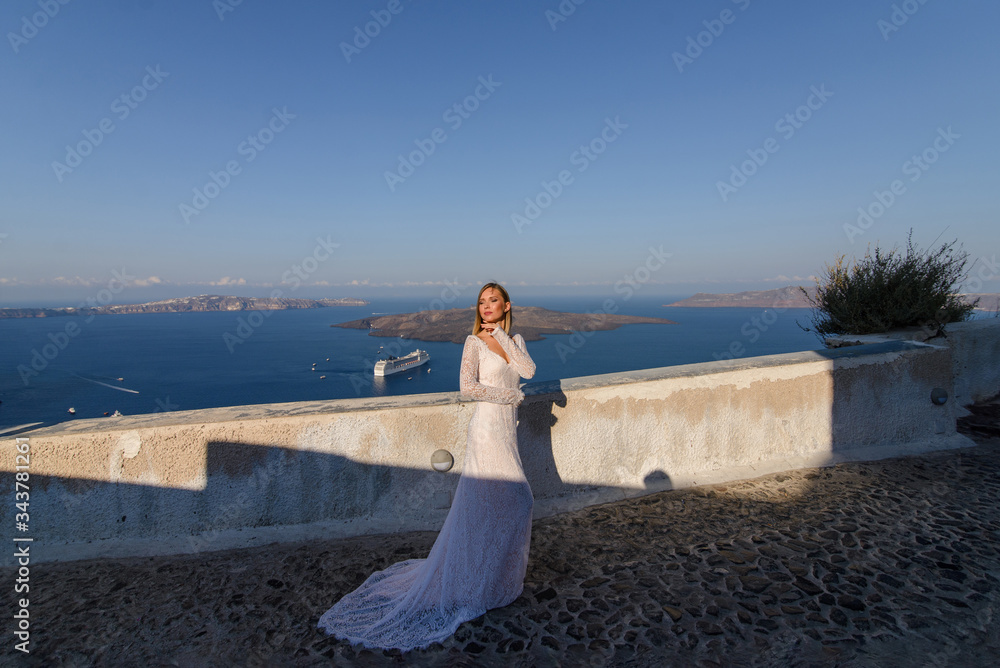 Beautiful bride In a white dress posing against the background of the Mediterranean Sea in Thira, Santorini. Beautiful bride In a white dress posing against the background of the Mediterranean Sea in Thira, Santorini.