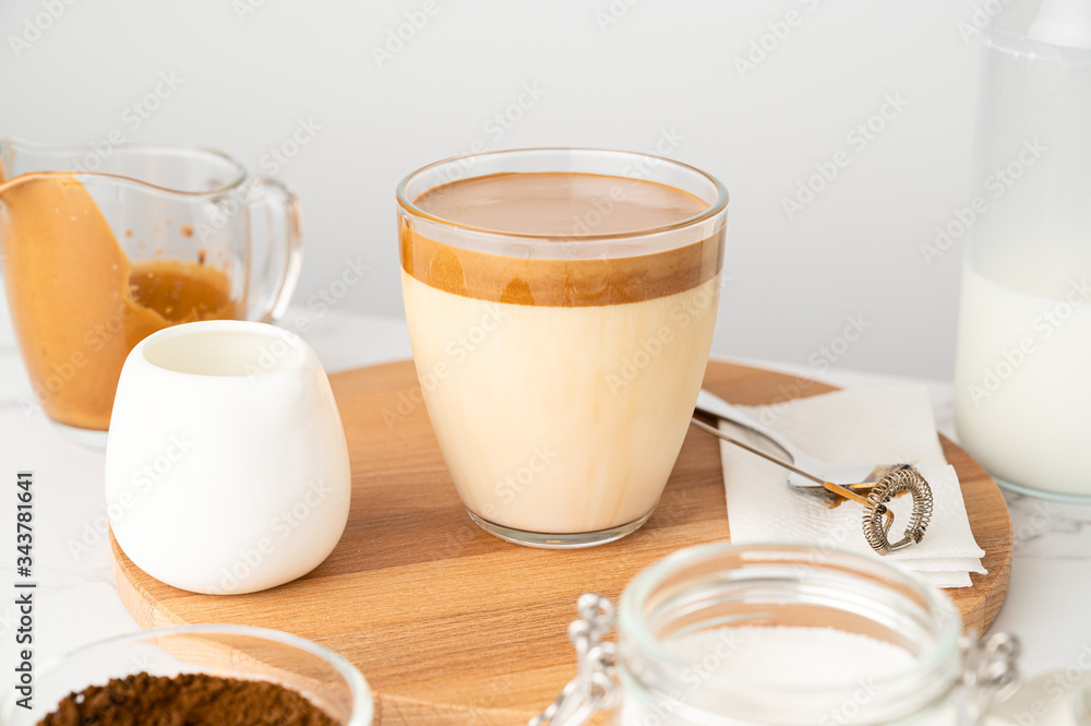 Closeup of Iced Dalgona coffee in glass cup and ingredients on light background. Trendy refreshment creamy whipped coffee. Korean coffee drink. Horizontal orientation Closeup of Iced Dalgona coffee in glass cup and ingredients on light background. Trendy refreshment creamy whipped coffee. Korean coffee drink. Horizontal orientation