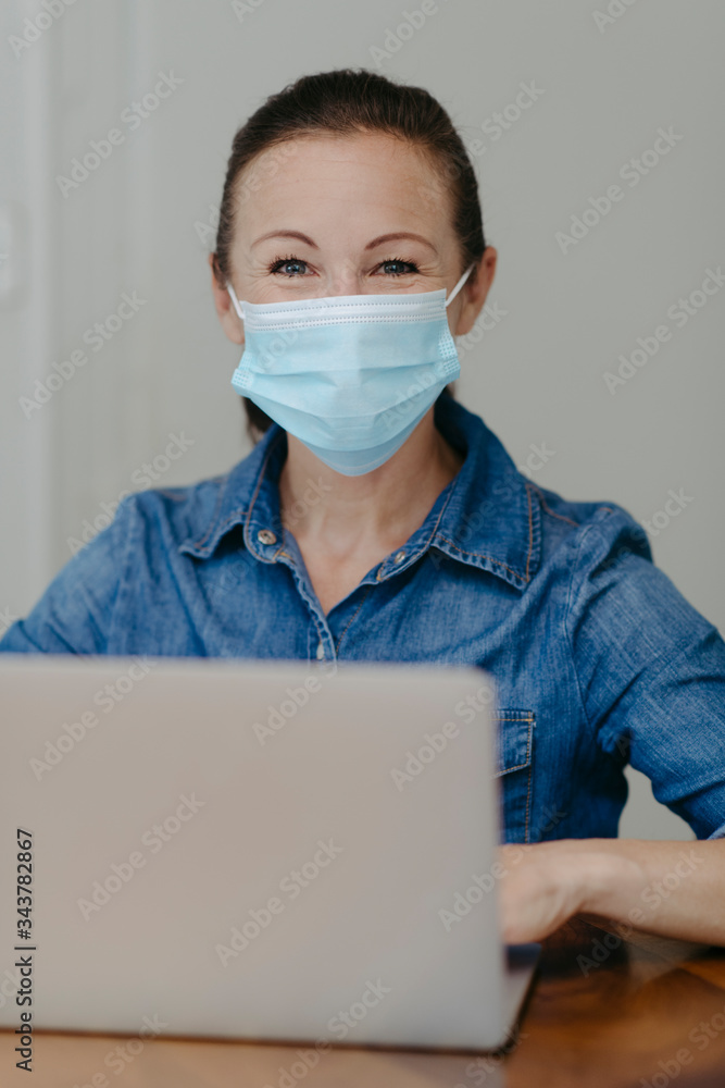 Frau beim Home-Office mit Mundschutzmaske