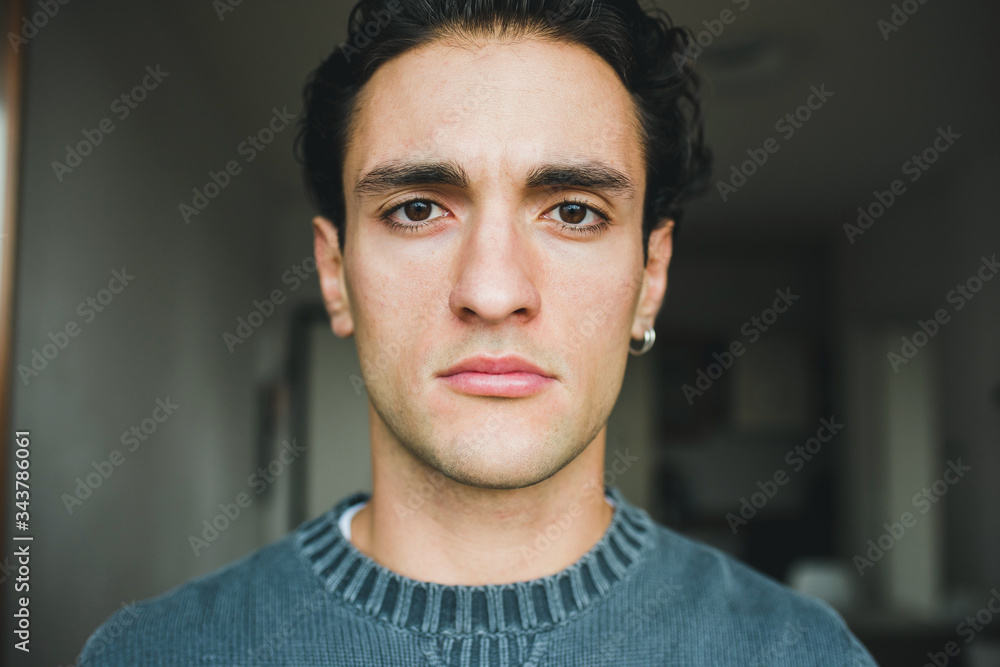 Naklejka premium Portrait handsome young caucasian man indoors at home posing staring at camera