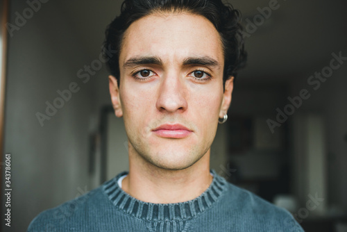 Portrait handsome young caucasian man indoors at home posing staring at camera