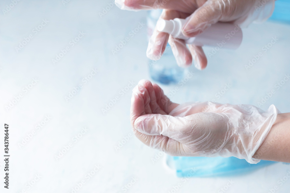 Naklejka premium hand disinfection, a woman disinfects hands with rubber gloves with a sanitizer, coronavirus
