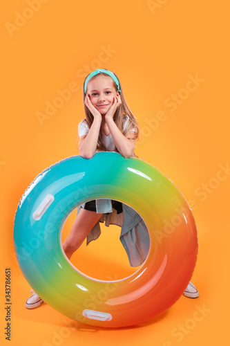 Happy child little girl with a swimming ring on a colored yellow background. Vacation concept