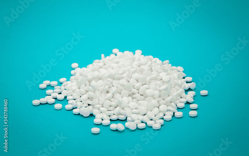 Large sprinkled handful of antiviral white pills on a blue background close-up