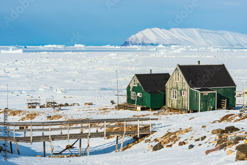 Green houses in front of frozen sea and mountains, Greenland.