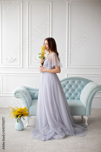 beautiful girl in a luxurious interior. restoration of antique furniture, interior design. a room with white plaster mouldings,a blue sofa upholstered in a blue velvet carriage tie. photo