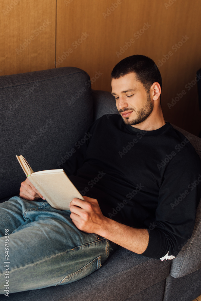 bearded and handsome man reading book in living room bearded and handsome man reading book in living room