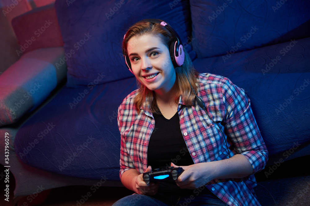 Naklejka premium Portrait of crazy playful Gamer enjoying Playing Video Games on Playstation indoors sitting on the sofa, holding Console Gamepad in hands, Xbox fans. Resting At Home, have a great Weekend