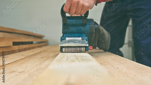 Φωτογραφία The carpenter process the wood by the belt sander