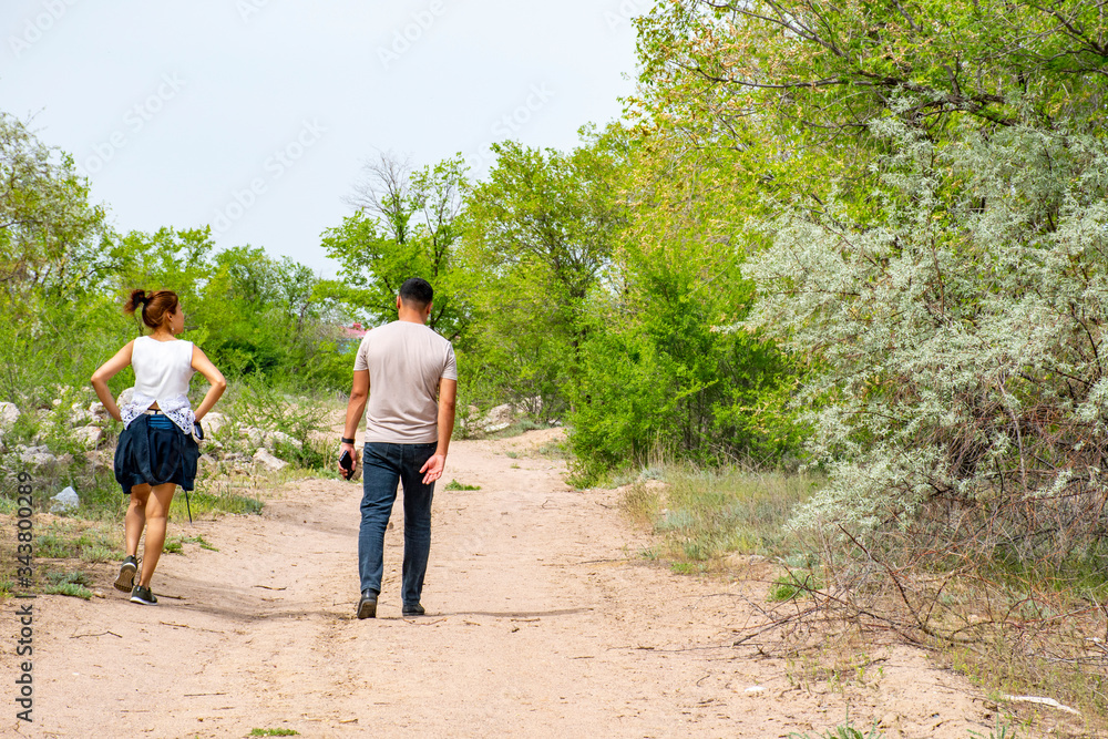 Fototapeta premium The guy with the girl are walking along the path.