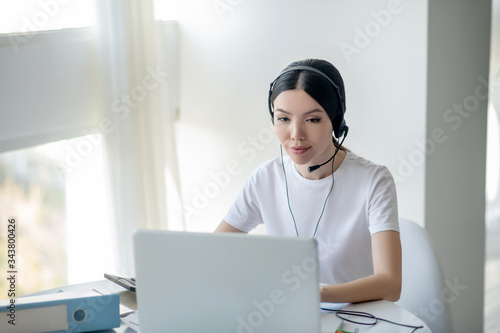 Brunette female working on laptop, wearing headphones