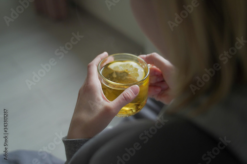 Sick woman drinks tea from a glass in at home