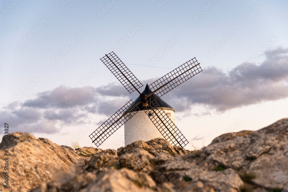 View of an old windmill, located on a hill in the town of Consuegra (Spain), on the traditional route of the Cervantes mills (Don Quixote), during sunset.