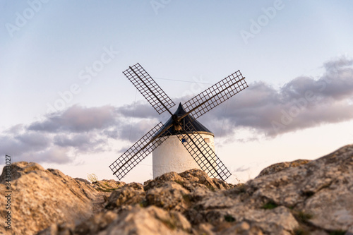 View of an old windmill, located on a hill in the town of Consuegra (Spain), on the traditional route of the Cervantes mills (Don Quixote), during sunset.