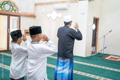 father and son praying together in the mosque. muslim people pray
