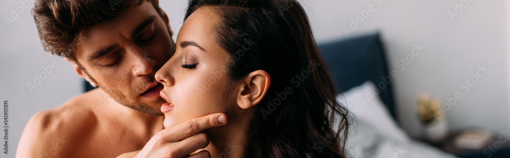 Man with closed eyes kissing passionate girl in bedroom, panoramic shot Man with closed eyes kissing passionate girl in bedroom, panoramic shot