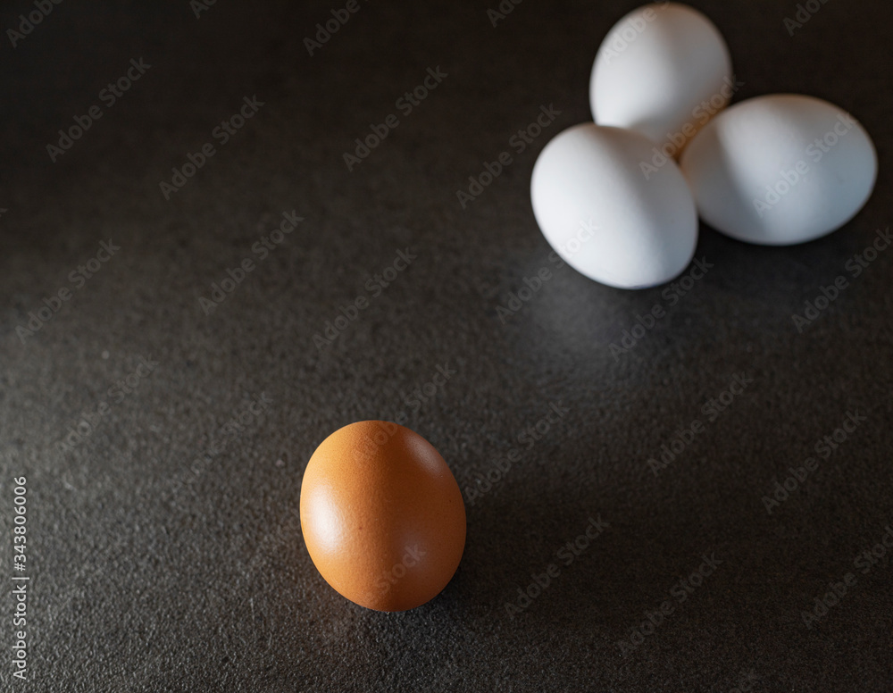 White eggs and brown eggs on a black background. Eggs on table. White eggs and brown eggs on a black background. Eggs on table.