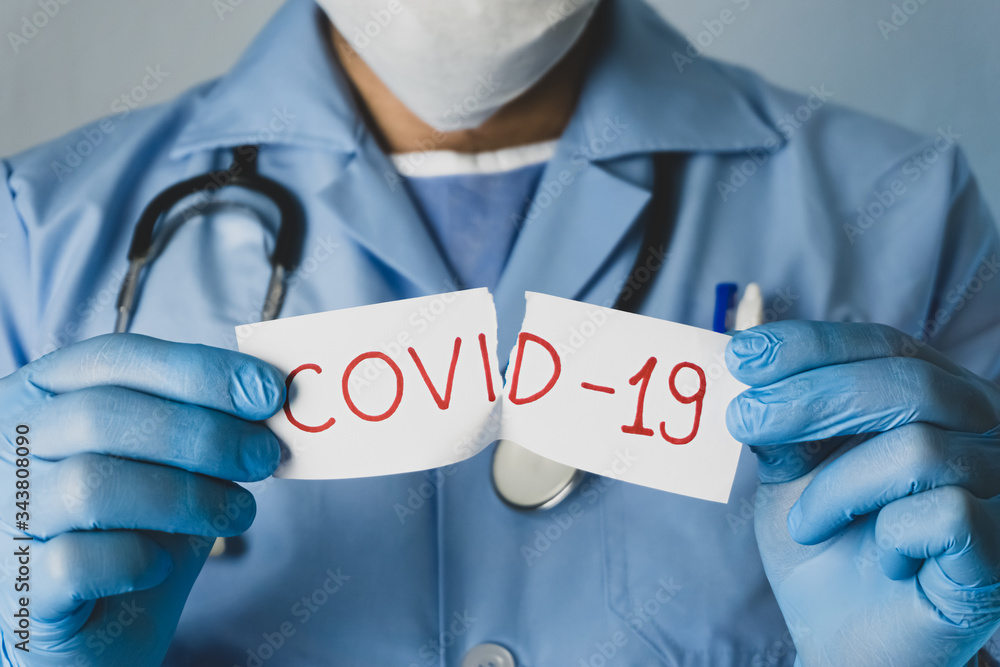 The doctor tears off the white paper that says Covid-19. Coronavirus outbreak concept. The doctor tears off the white paper that says Covid-19. Coronavirus outbreak concept.