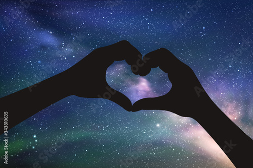 Heart shaped hands at night. Romantic vector illustration with hand gesture silhouette on starry sky. Space dark background with Milky Way and green aurora borealis