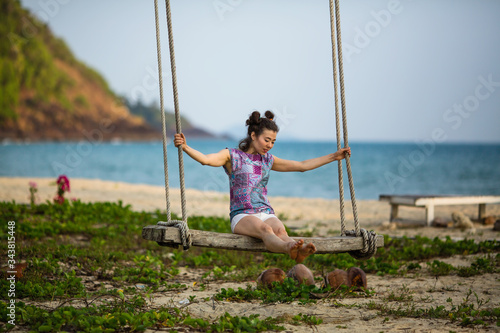 Multicultural asian woman on a swing on a tropical beach.