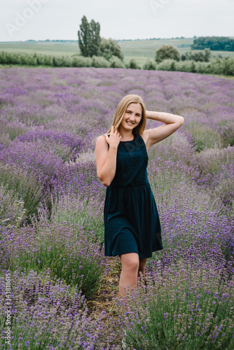 Fototapeta Naklejka Na Ścianę i Meble -  Beautiful girl in dress stand on purple the lavender field. Beautiful woman walk in the lavender field on sunset in France. Soft focus. Enjoy on the floral glade, summer nature.