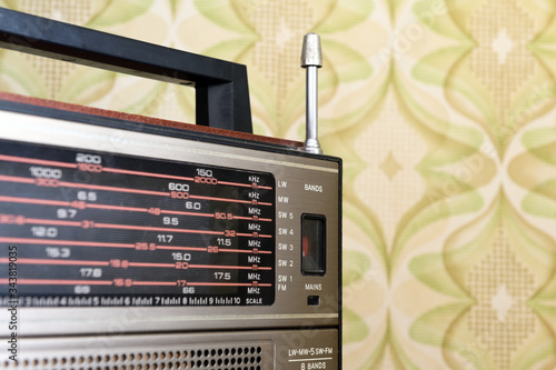 Antique radio receiver of an old nightstand in a vintage room with old-fashioned wallpaper, tinted and added noise