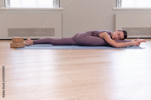 Side view of pacified calm slim caucasian sportswoman in purple suit doing the splits. Yoga instructor charming girl doing hanumanasana. Advertising space