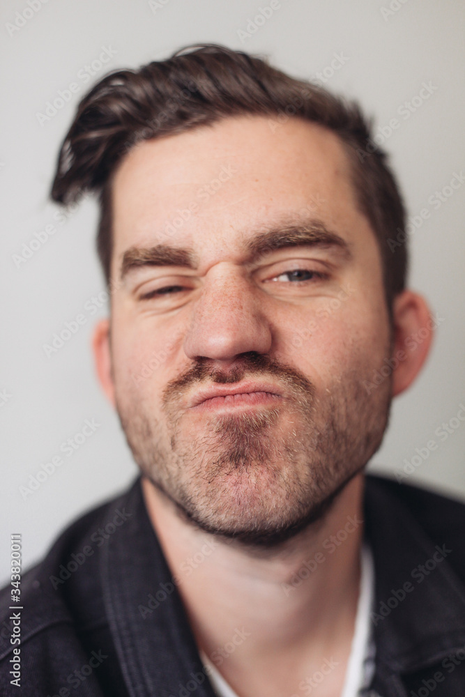 A portrait of a young handsome man making silly faces, grey background A portrait of a young handsome man making silly faces, grey background