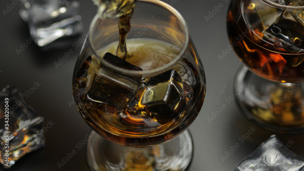 Pouring whiskey, cognac into glass. Black background. Pour of alcohol drink Pouring whiskey, cognac into glass. Black background. Pour of alcohol drink
