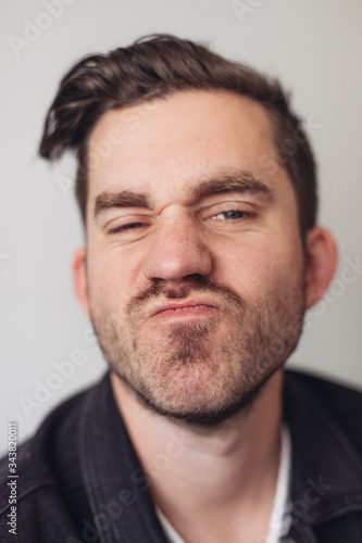 A portrait of a young handsome man making silly faces, grey background