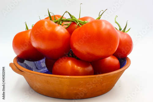 ripe fresh bunch red tomato on vine in a terracotta bowl isolated on white background