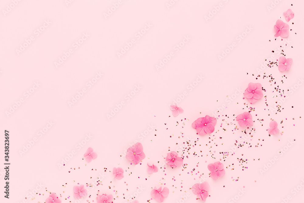 Frame of flowers and gold confetti spread on pink background. Spring Holidays, Birthday, Mothers Day, wedding. Copy space.