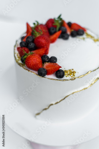 A beautiful white cake with cheese cream, meringues, chocolate and fresh Berries on a white background. The original idea for a wedding cake or birthday cake.